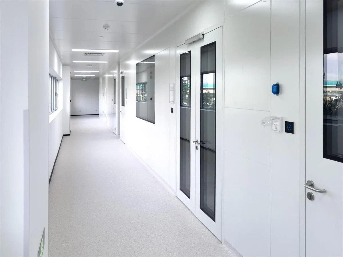 Bright corridor inside a finished modular cleanroom facility with sealed wall panels and flush vision doors