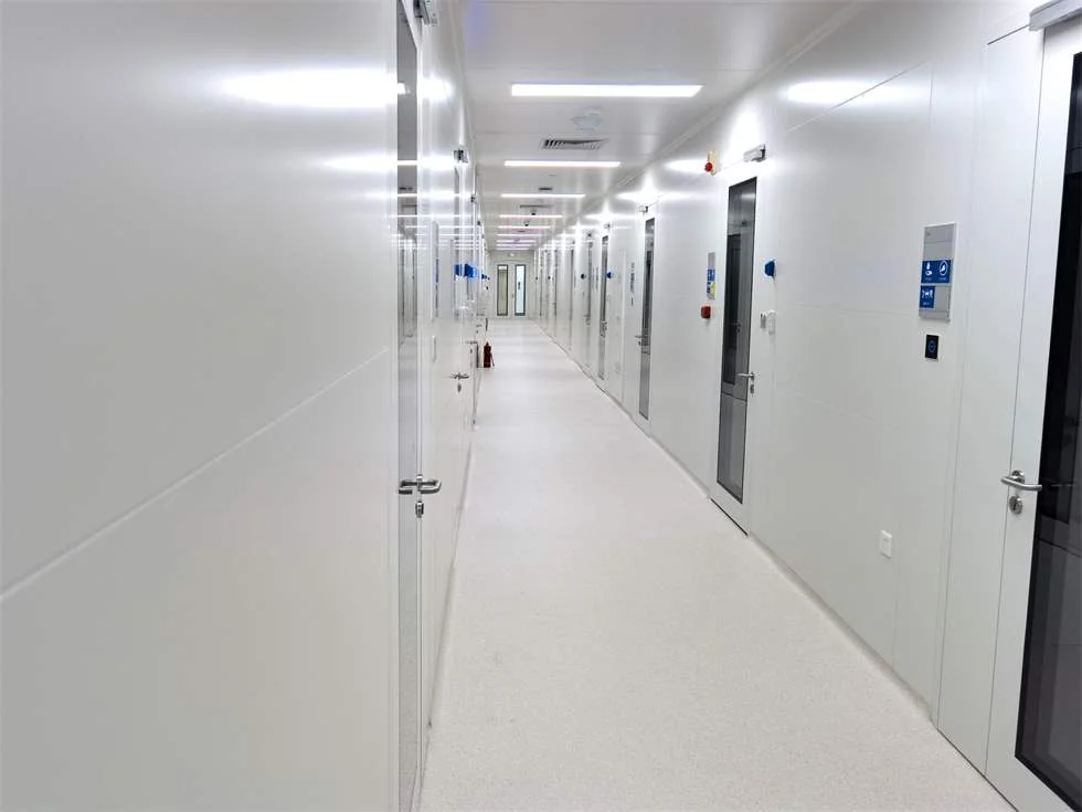 Bright cleanroom corridor with sealed wall panels, flush ceiling lighting and cleanroom doors